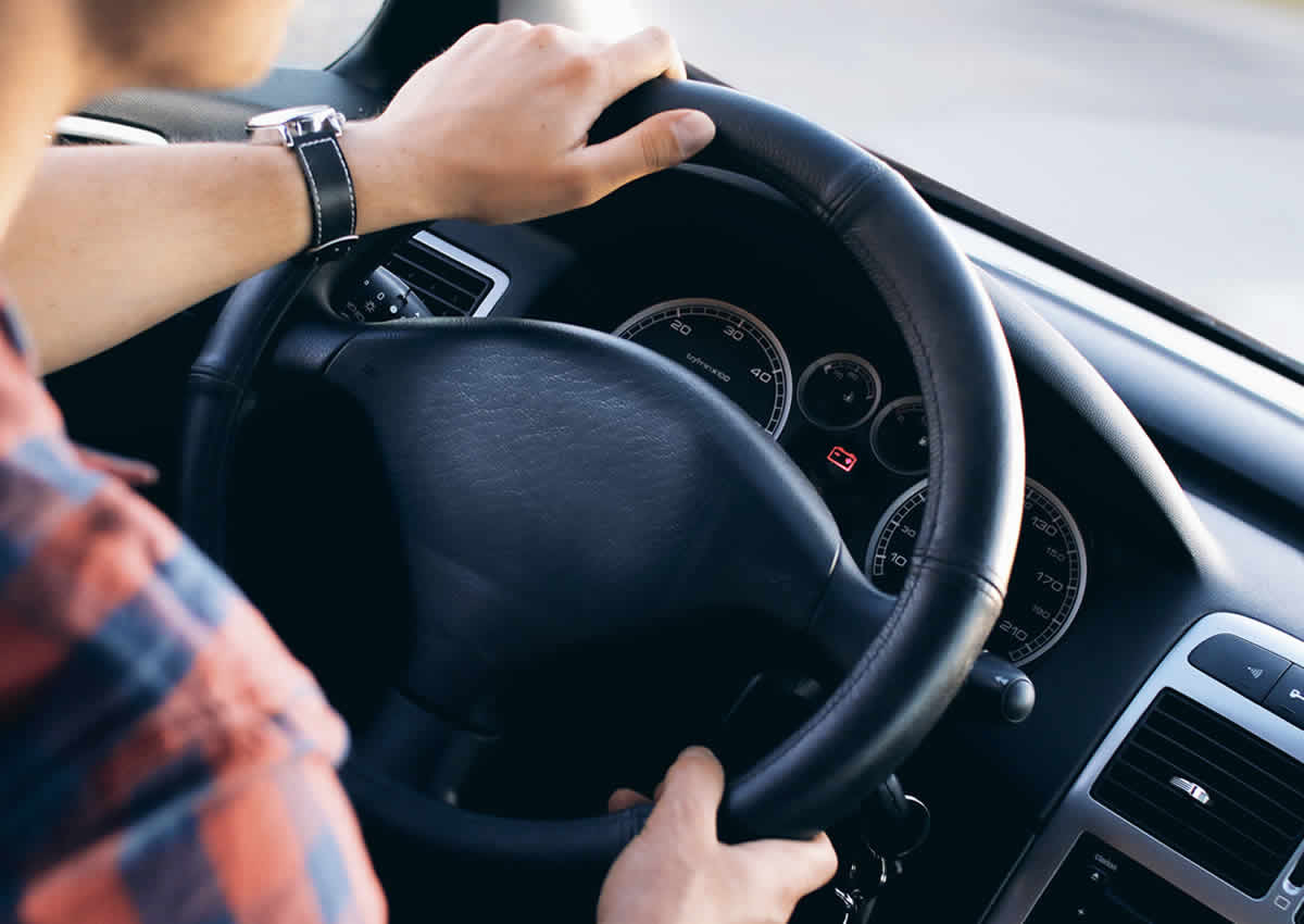 Man driving car with a serious warning light illuminated on the dashboard